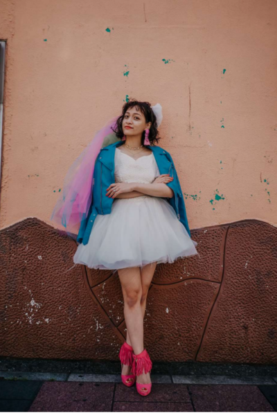 full length photo of a bride wearing a short white dress with a turquoise cardigan
